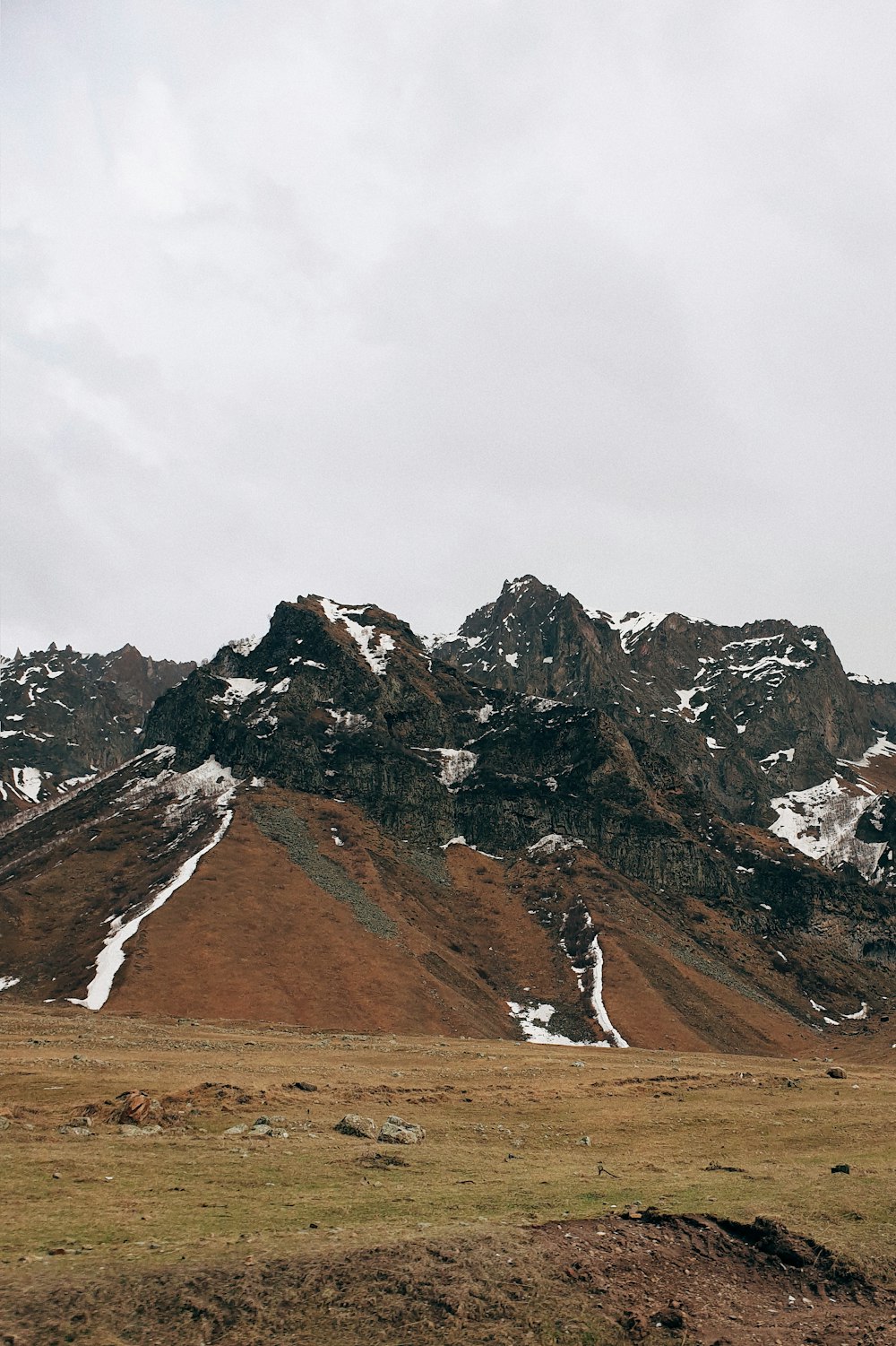 person walking on brown field near brown and white mountain during daytime