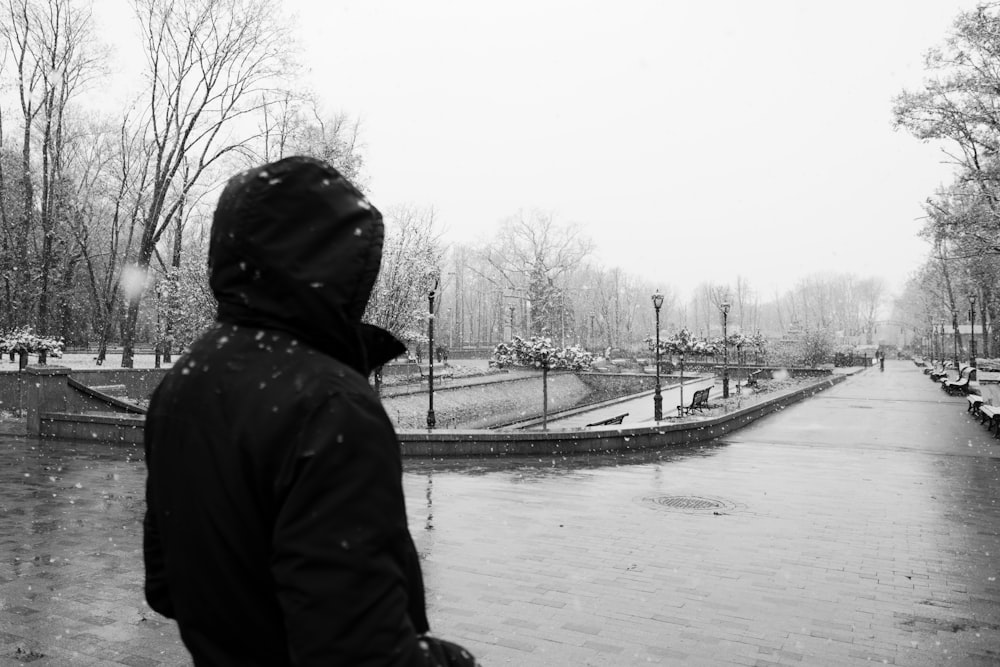 person in black hoodie standing near river