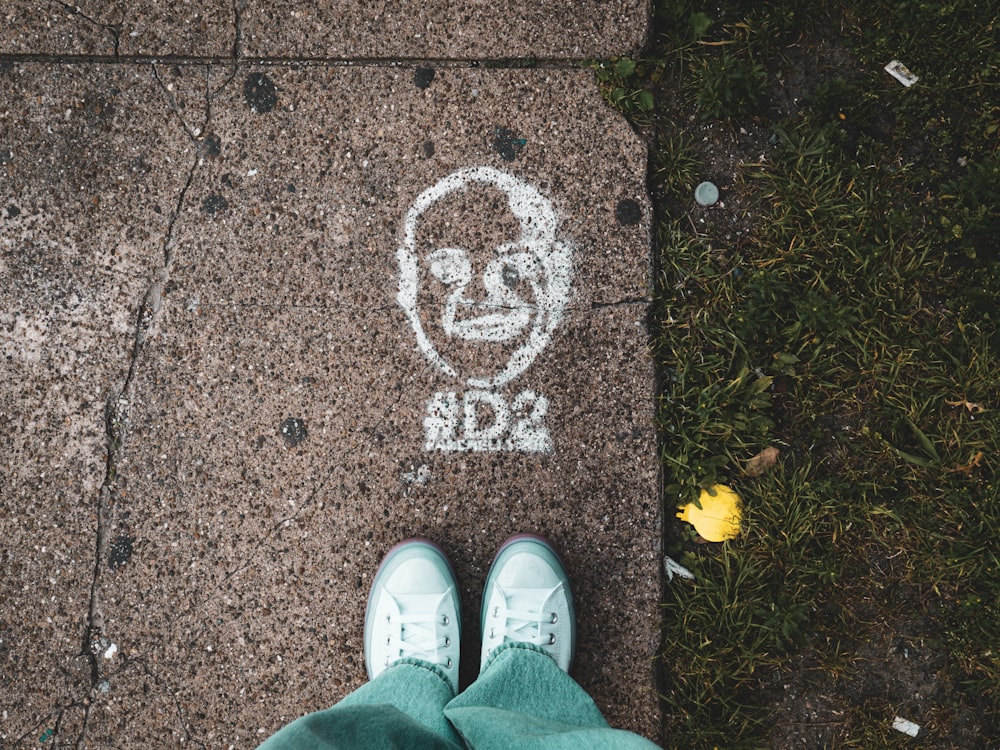 person in white sneakers standing on brown concrete floor