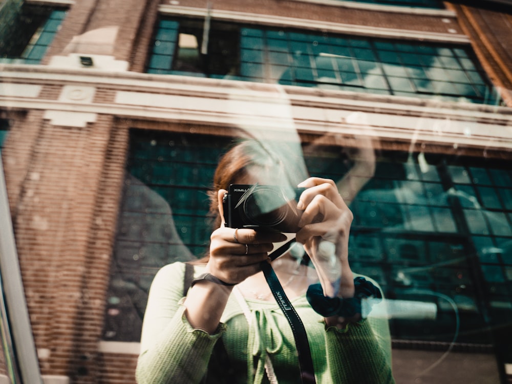 woman in white sweater holding black camera