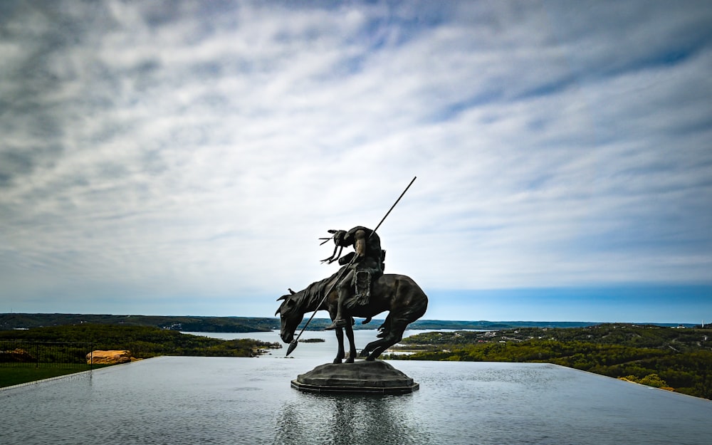 man riding horse statue under white clouds during daytime