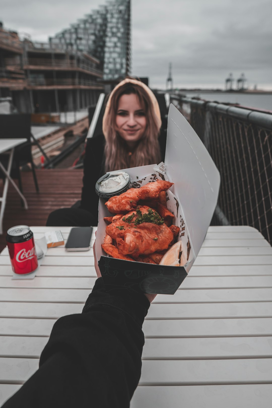 woman in black long sleeve shirt holding white paper bag with cooked food