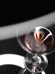 Close-up of a wine glass catching light with a rich red wine inside.