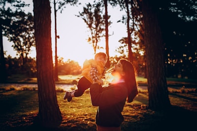 A serene mother gently holding her child's hand in a sunlit garden.