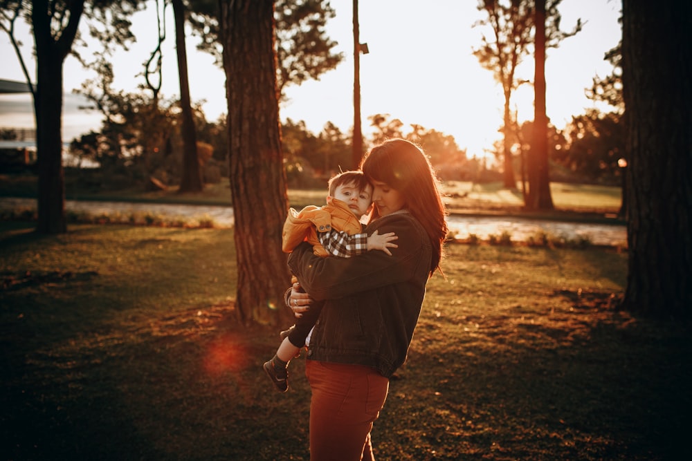 woman in brown long sleeve shirt carrying baby in white shirt