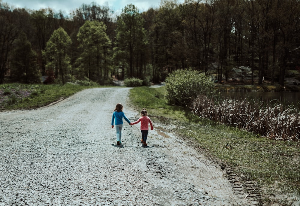 girl in red jacket walking on dirt road during daytime