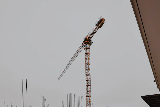 Steel reinforcement bars stacked at a busy construction site with cranes in the background.