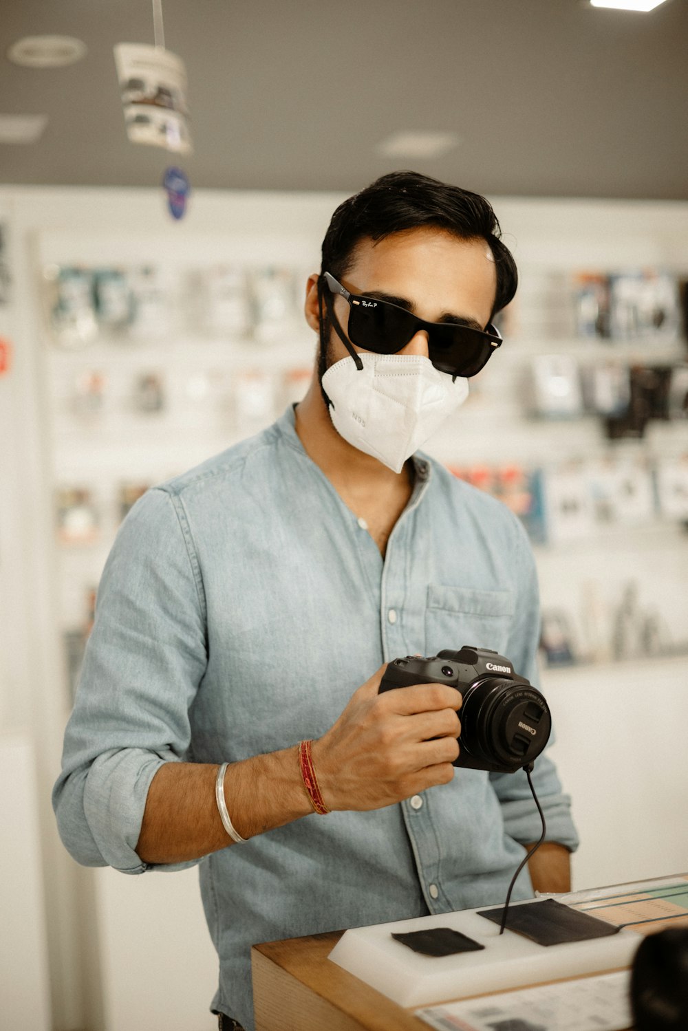 man in blue dress shirt wearing black sunglasses holding black dslr camera