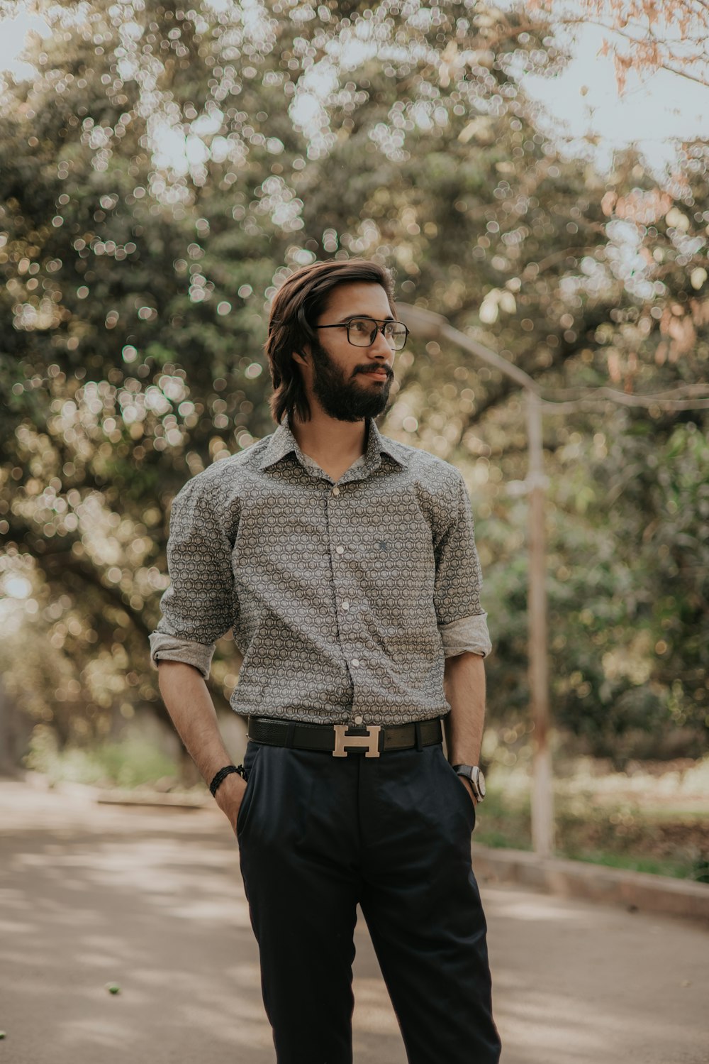 woman in blue dress shirt and black pants standing near green trees during daytime