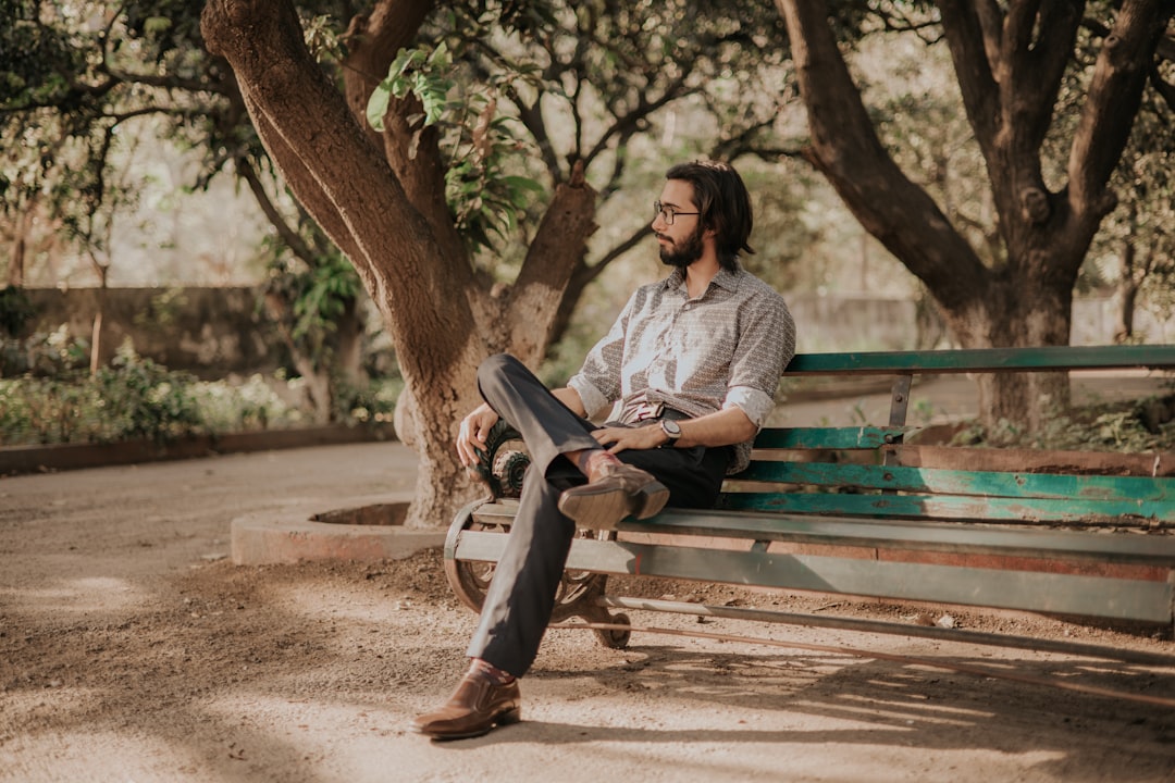 woman in gray jacket sitting on green wooden bench during daytime