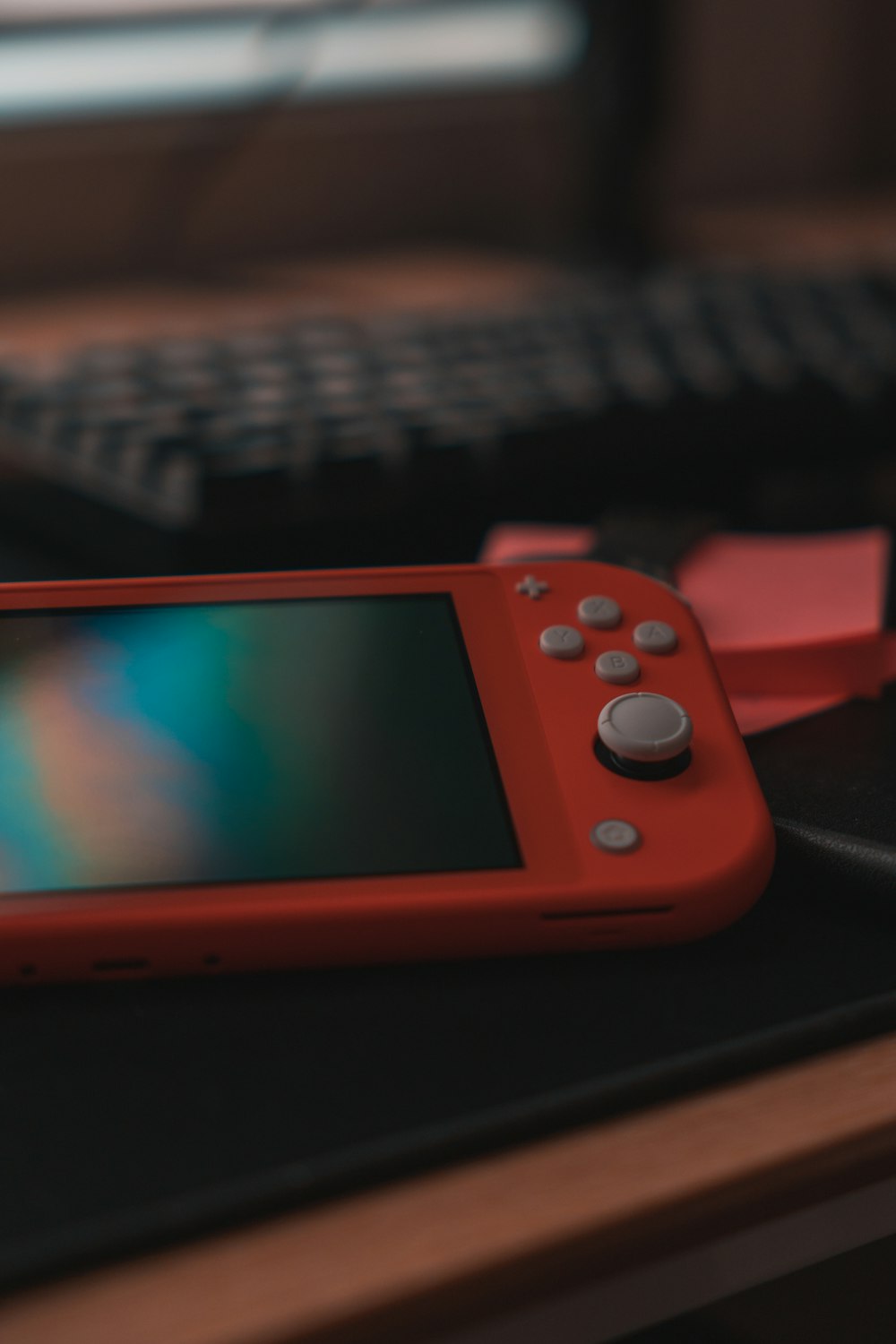 red nintendo switch on black computer keyboard