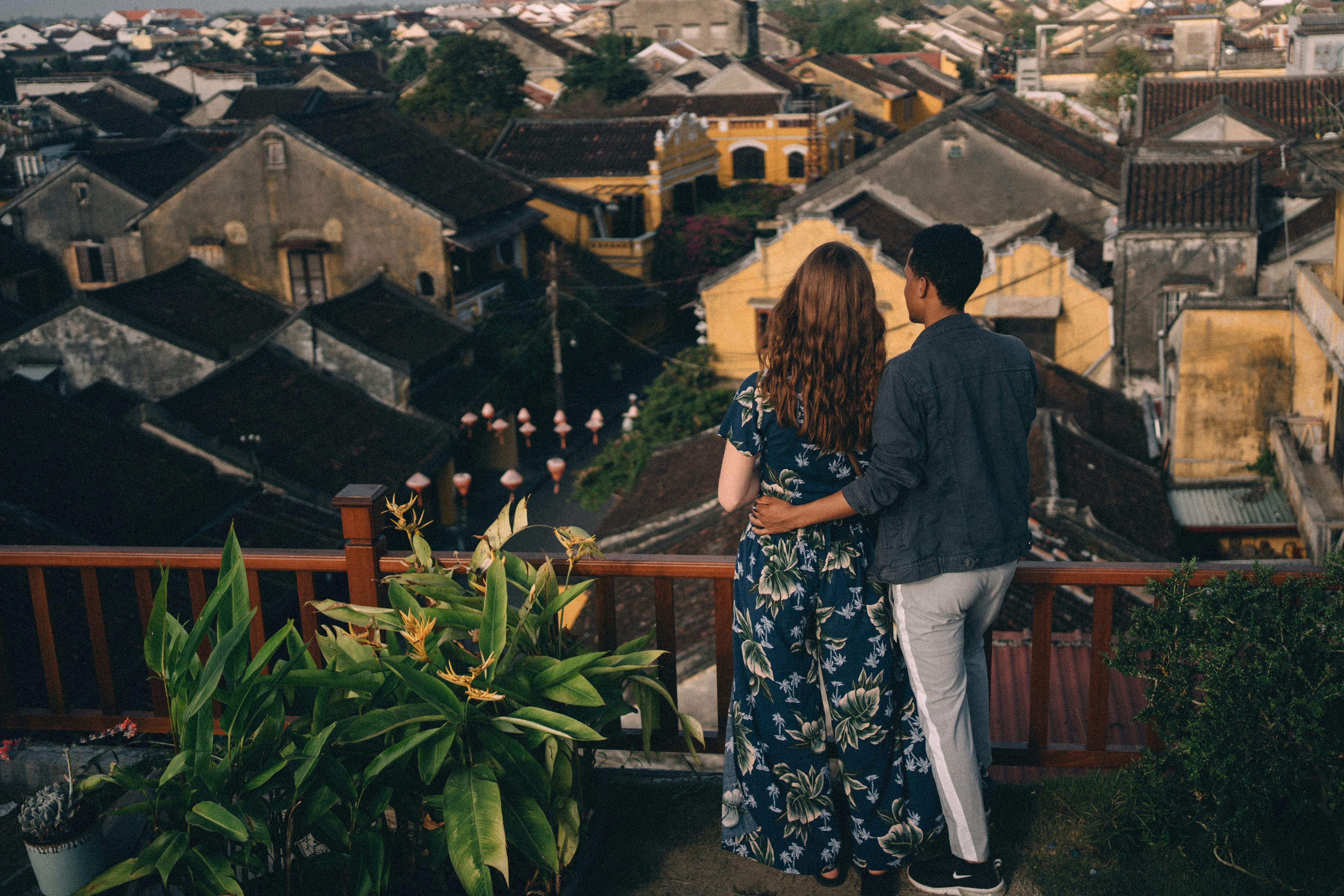 woman in blue and white floral dress standing on brown wooden fence during daytime