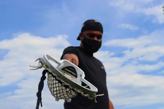 man in black hoodie holding white and black basketball hoop