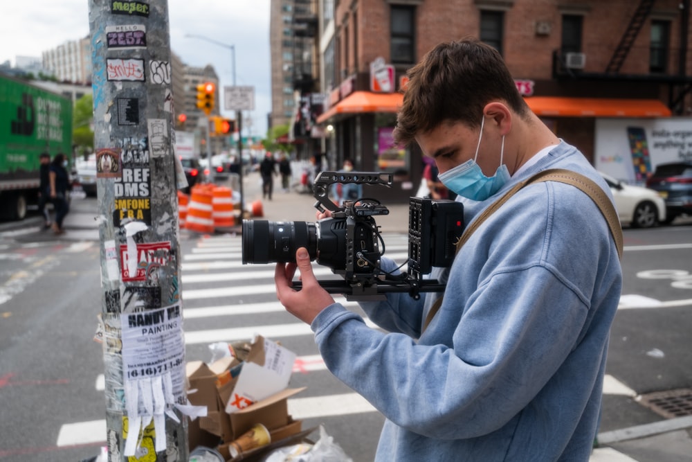 man in blue jacket holding black dslr camera