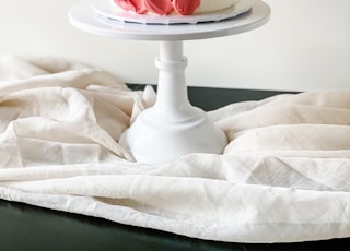white and red floral ceramic vase on white textile