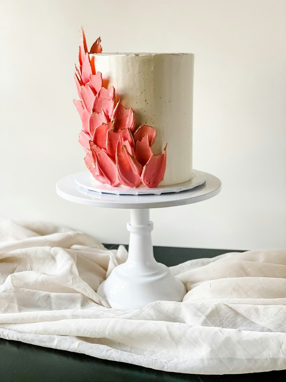 white and red floral ceramic vase on white textile