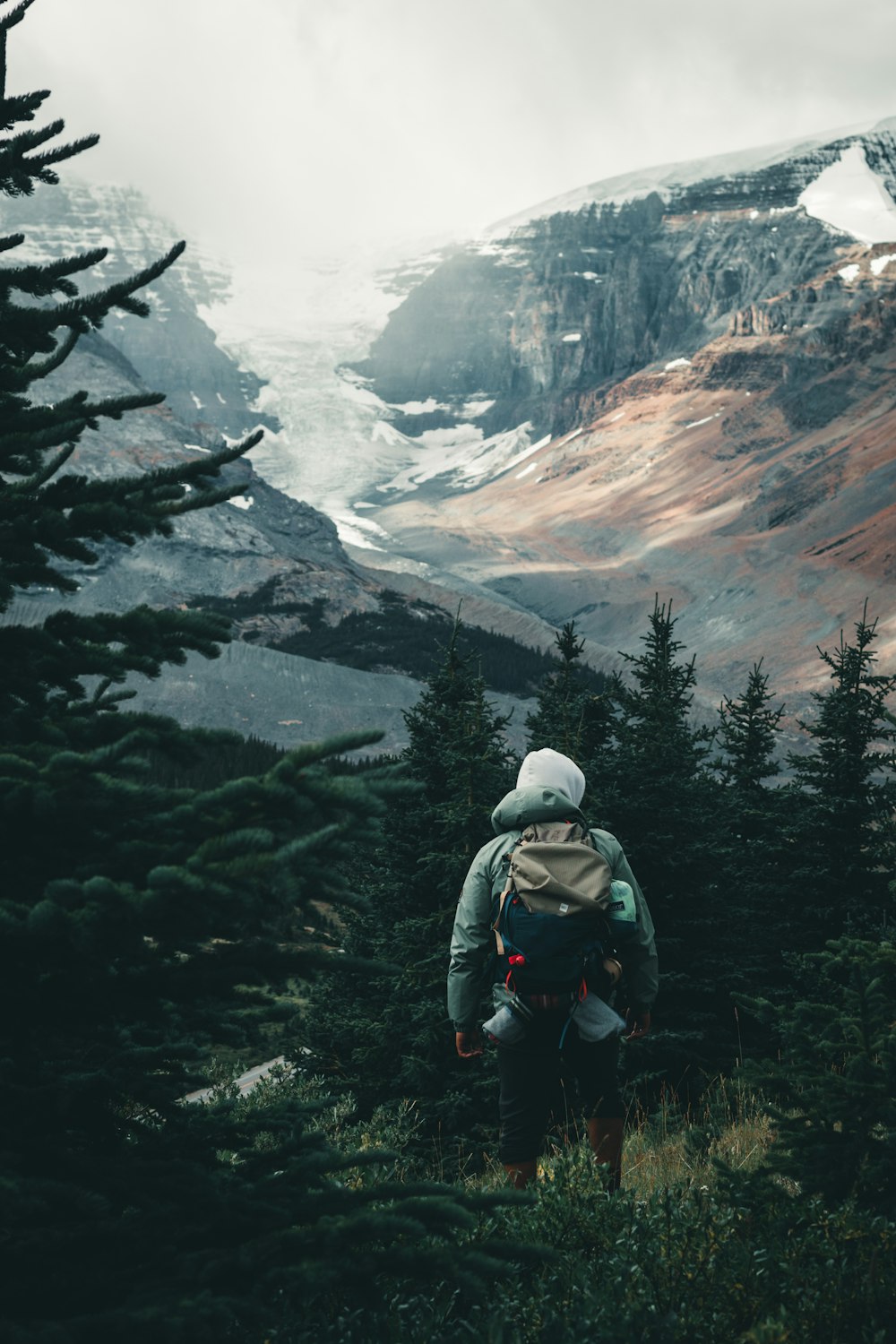 person in gray jacket and black backpack sitting on rock formation during daytime