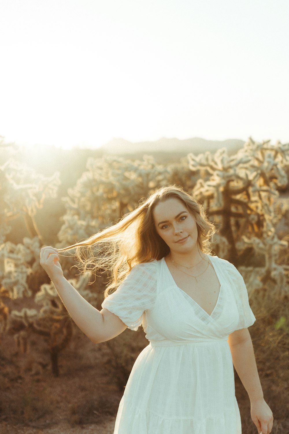 woman in white dress standing on brown grass field during daytime