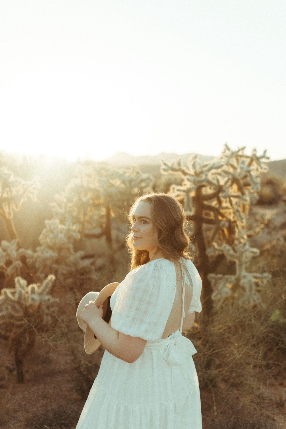 woman in white dress standing on brown grass field during daytime