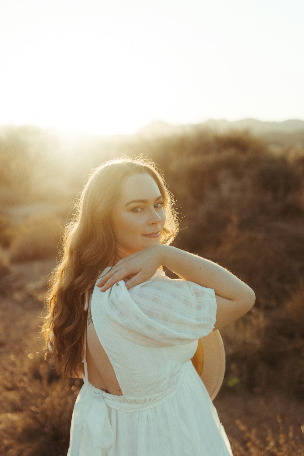 woman in white tank top standing on brown grass field during daytime