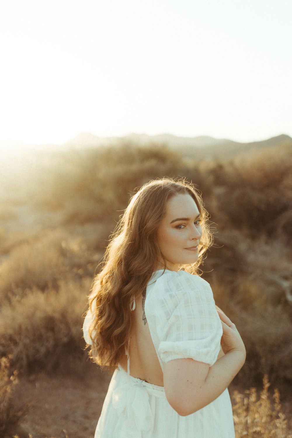 woman in white long sleeve shirt standing on brown grass field during daytime