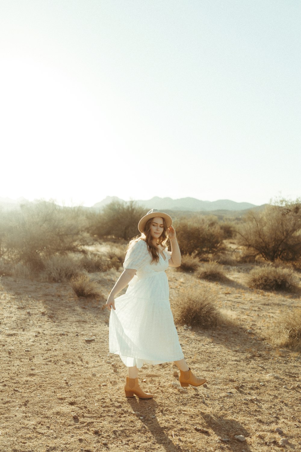 woman in white dress standing on brown field during daytime