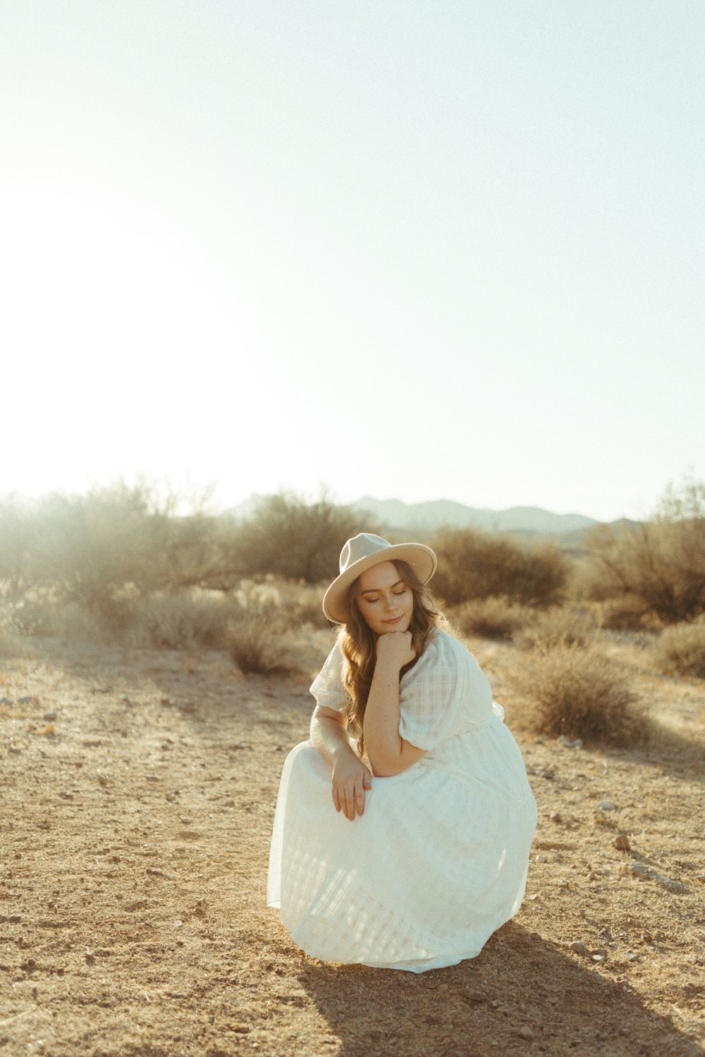 woman in white long sleeve dress standing on brown field during daytime