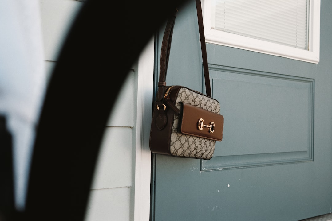 brown and black leather sling bag hanged on door