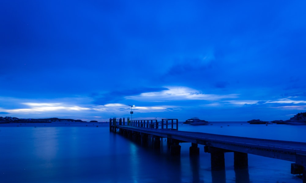 brown wooden dock on sea under blue sky during daytime