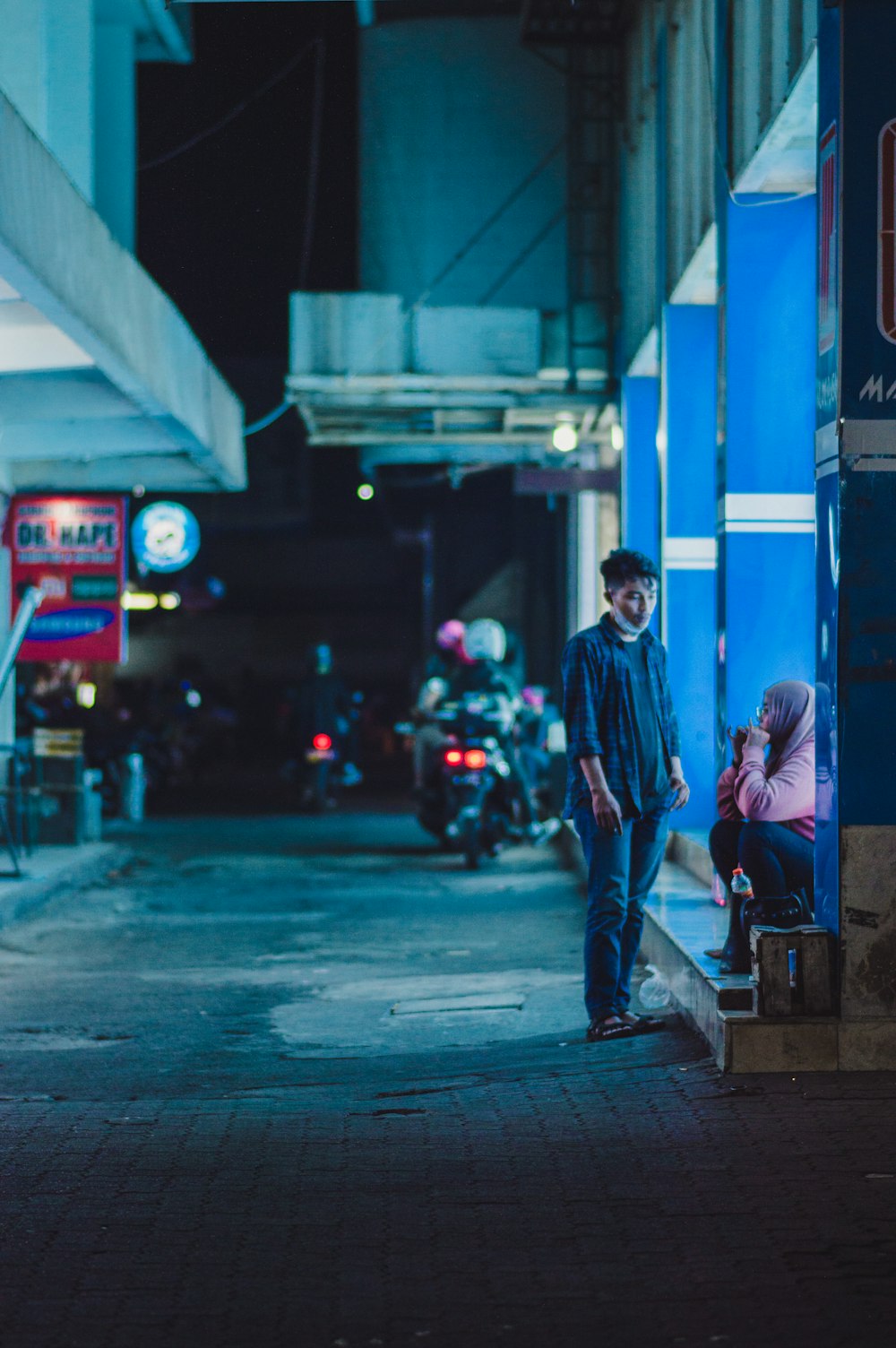 Hombre en chaqueta azul caminando en la acera durante la noche