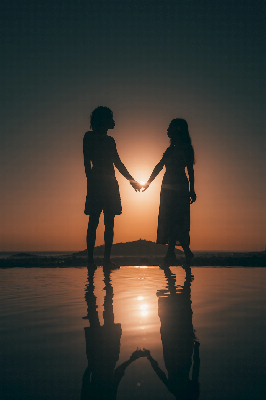 Siluet pasangan menikmati matahari terbenam di pantai Bali