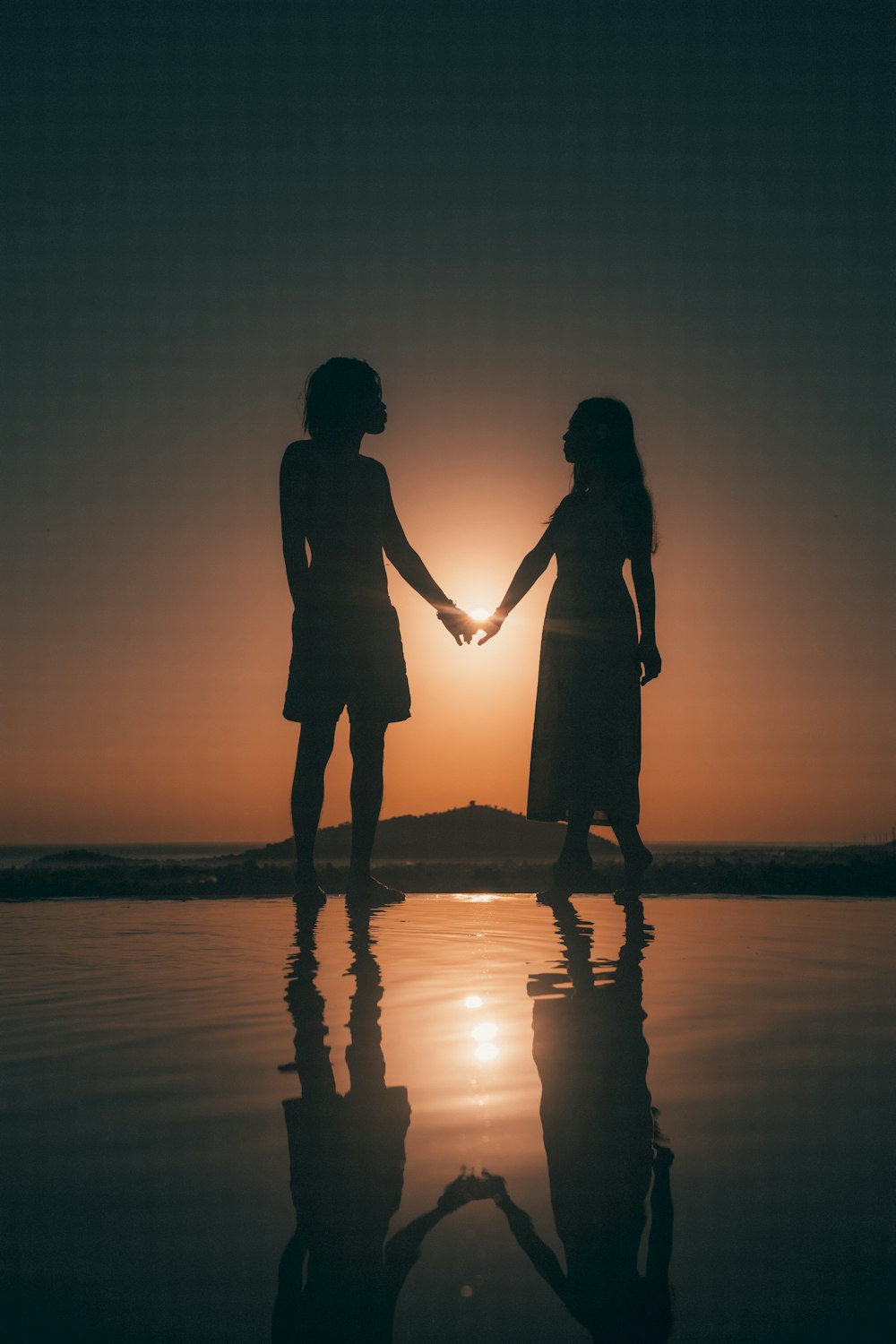 silhouette of couple kissing on beach during sunset