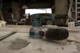 Close-up of a well-used power drill resting on a wooden workbench.