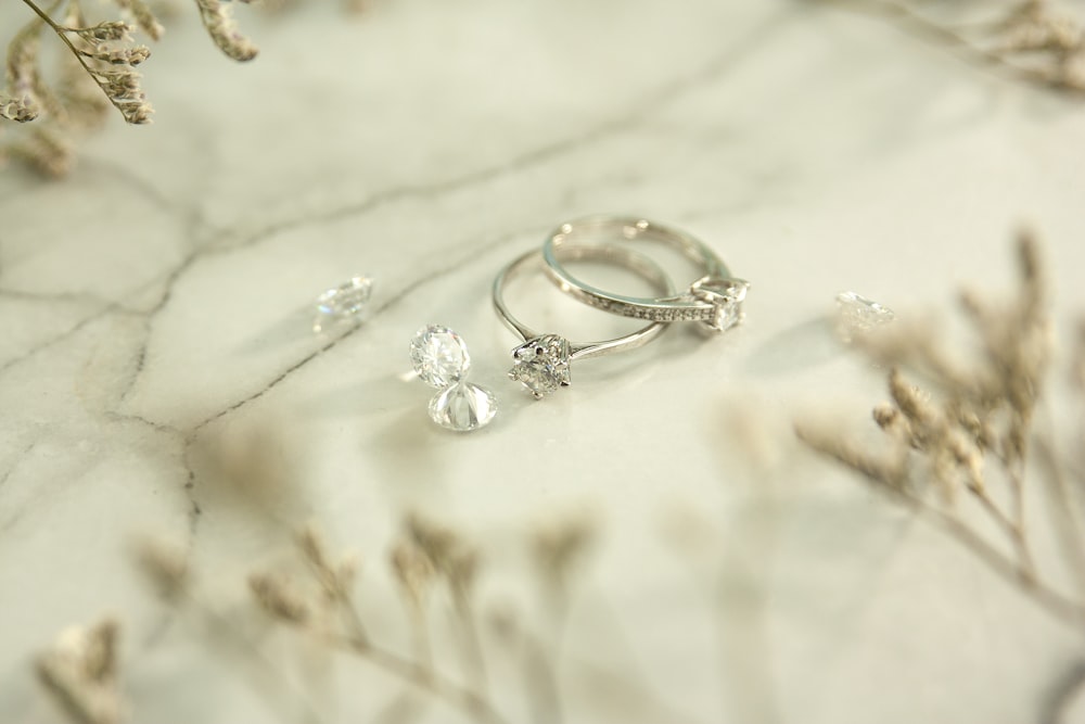 silver and diamond ring on white textile