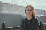 Person wearing smart glasses outdoors, with cityscape blurred in background.