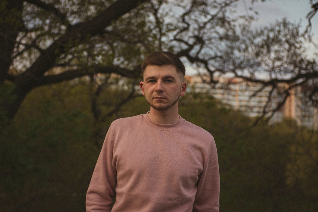 man in brown crew neck long sleeve shirt standing near trees during daytime