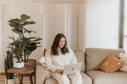 woman in white long sleeve shirt sitting on brown sofa chair