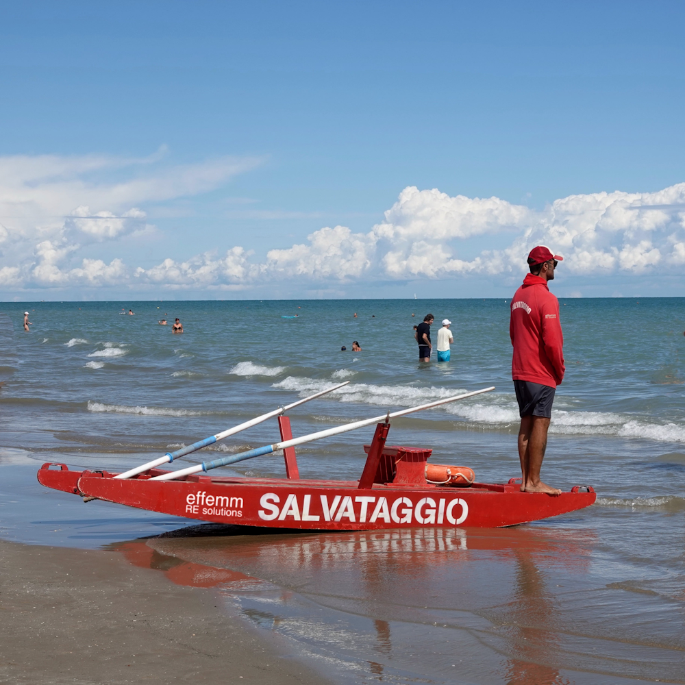 hombre con camiseta blanca y pantalones cortos azules de pie en kayak rojo y blanco en el mar