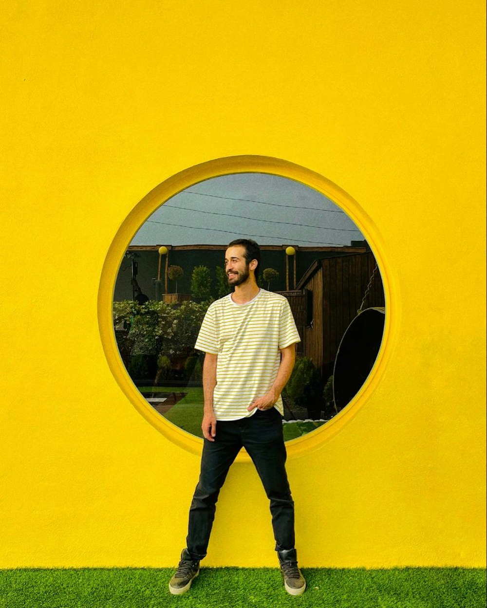 man in white dress shirt and black pants standing in front of round mirror