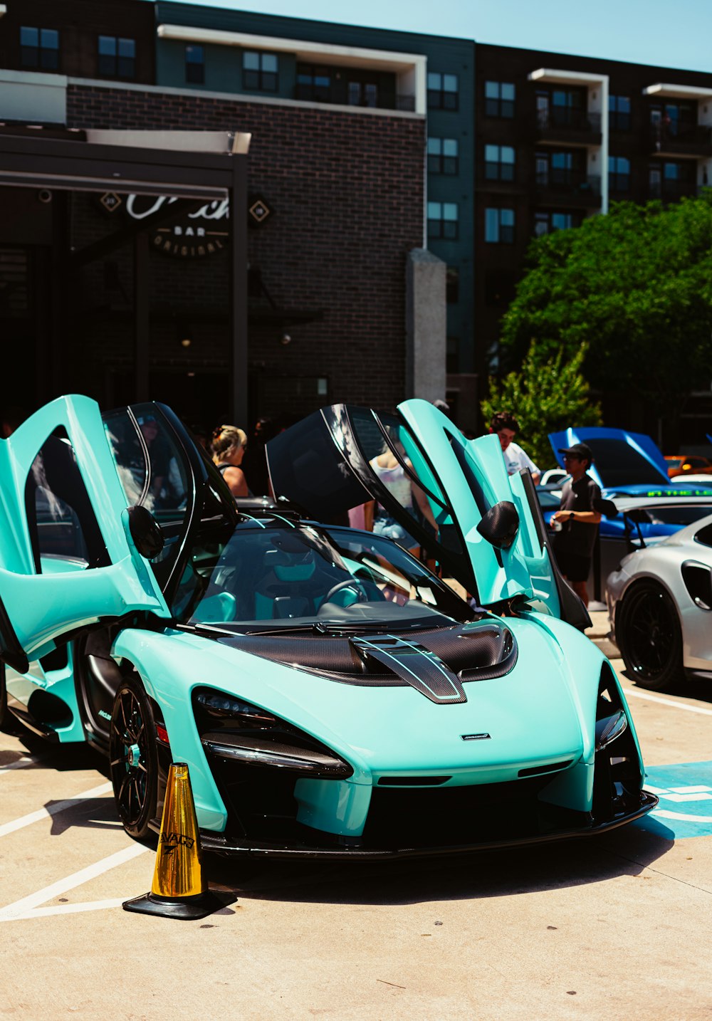 blue and black sports car parked beside blue car during daytime