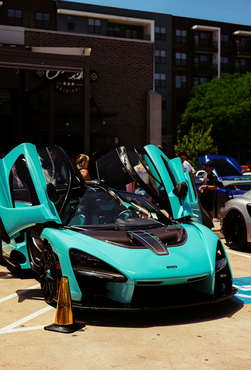 blue and black sports car parked beside blue car during daytime