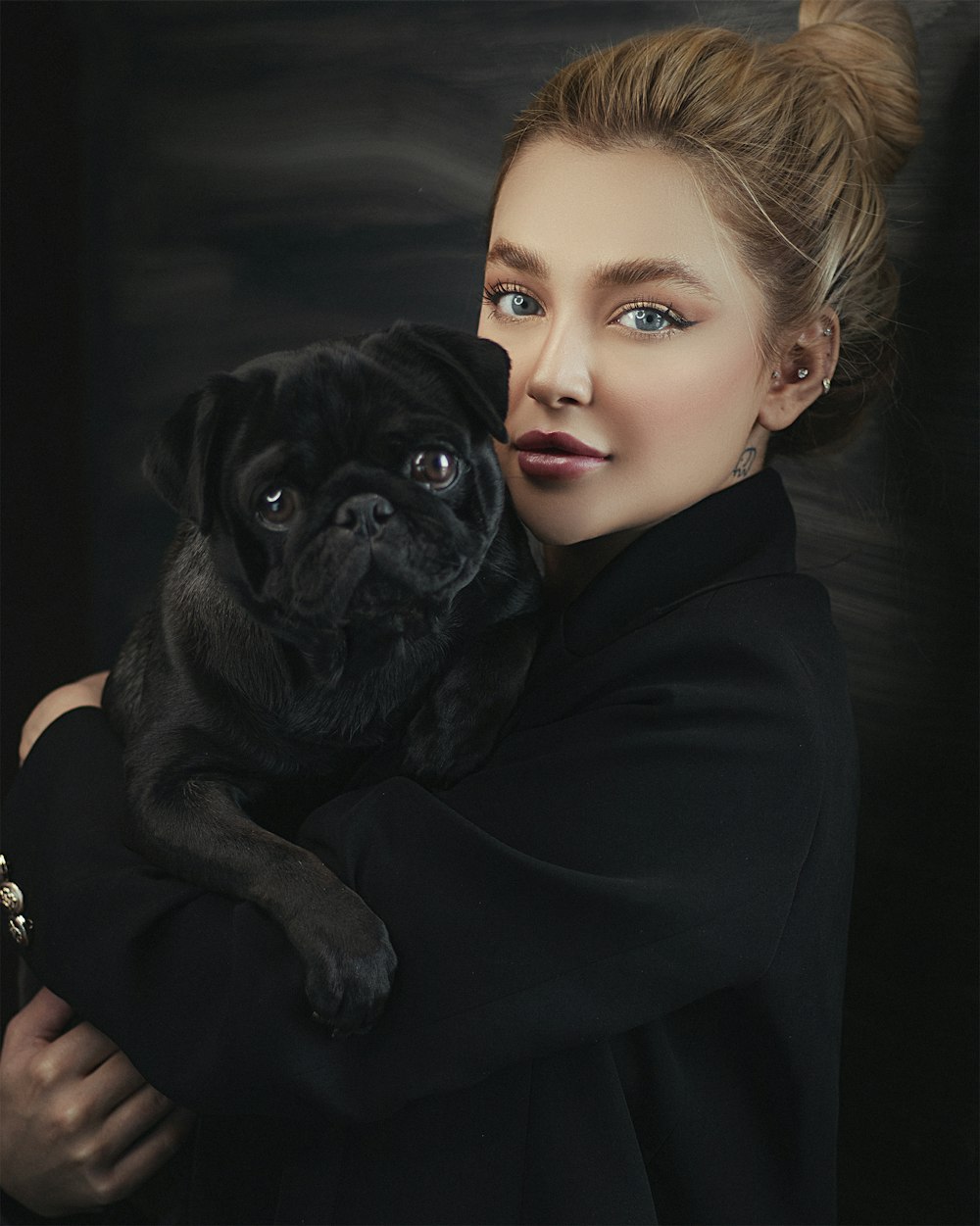 woman in black long sleeve shirt holding black pug