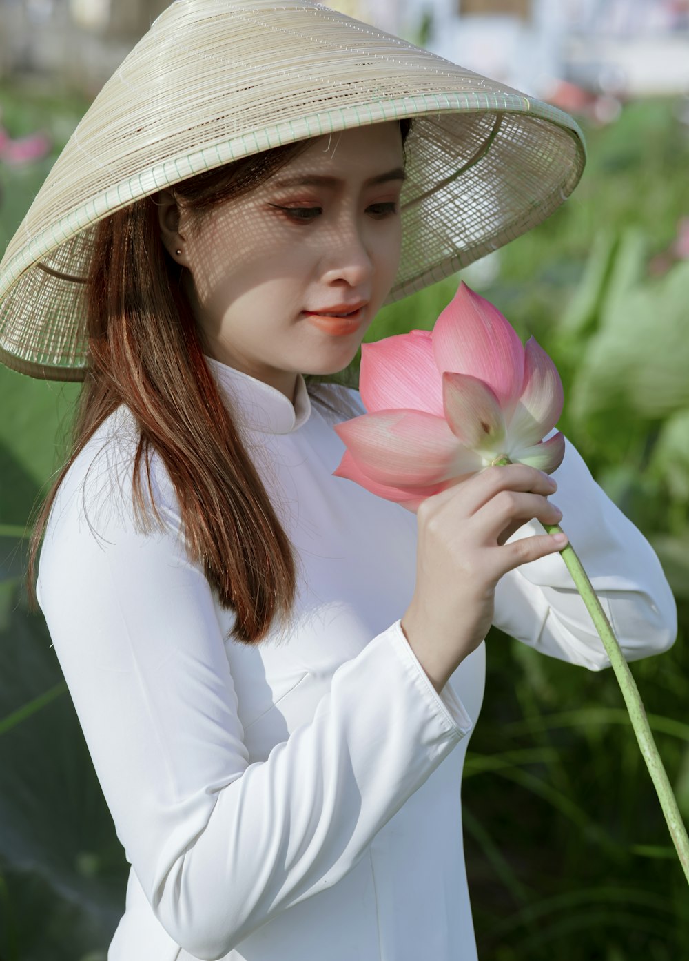 woman in white long sleeve shirt holding pink and yellow flower