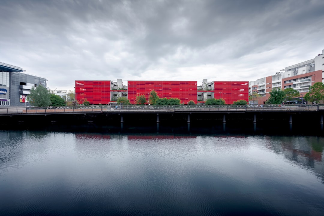 orange and white concrete building beside body of water under cloudy sky during daytime