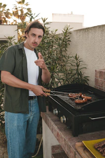 man in black crew neck t-shirt and blue denim jeans holding black frying pan