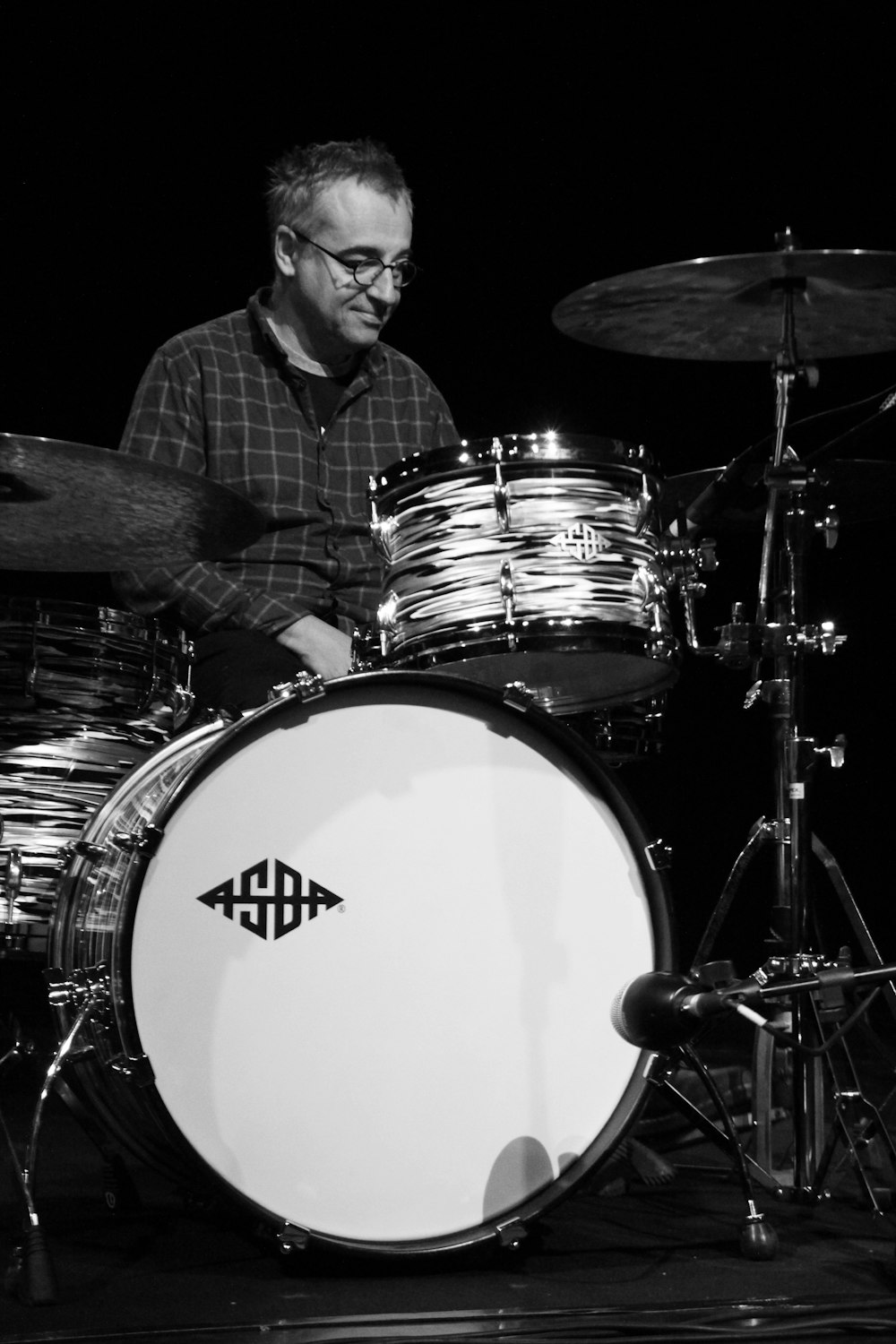 man in black and white plaid dress shirt playing drum