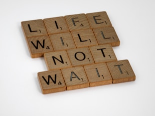 brown wooden blocks on white surface explaining that life will not wait for you to make decisions