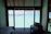 A cozy guestroom bathed in soft natural light with a view of the turquoise ocean through the window.