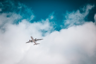 white airplane under blue sky and white clouds during daytime