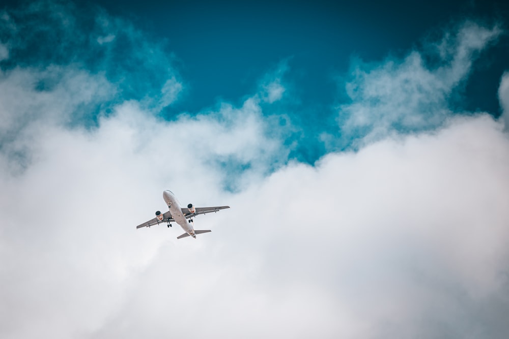 Avión blanco bajo el cielo azul y nubes blancas durante el día